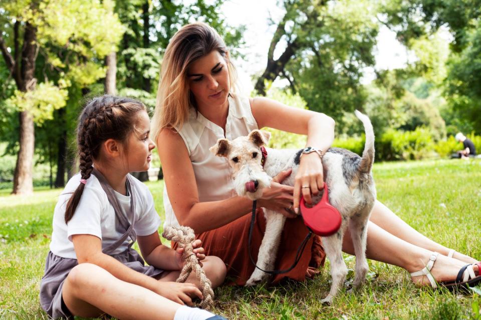 Mom and daughter sitting with dog outside.